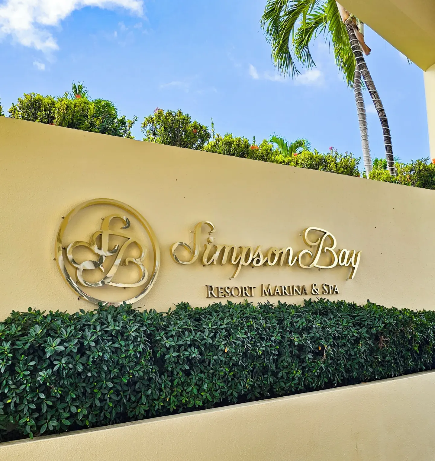 Entrance wall sign for Simpson Bay Resort, Marina & Spa with palms and greenery.