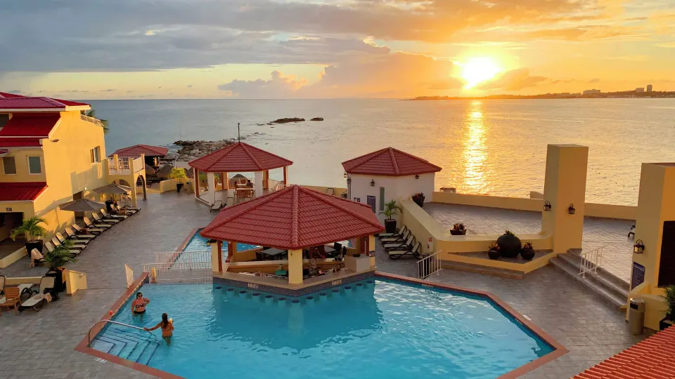 Sunset over the oceanfront pool and red-roofed pavilions at Simpson Bay Resort, Marina & Spa.