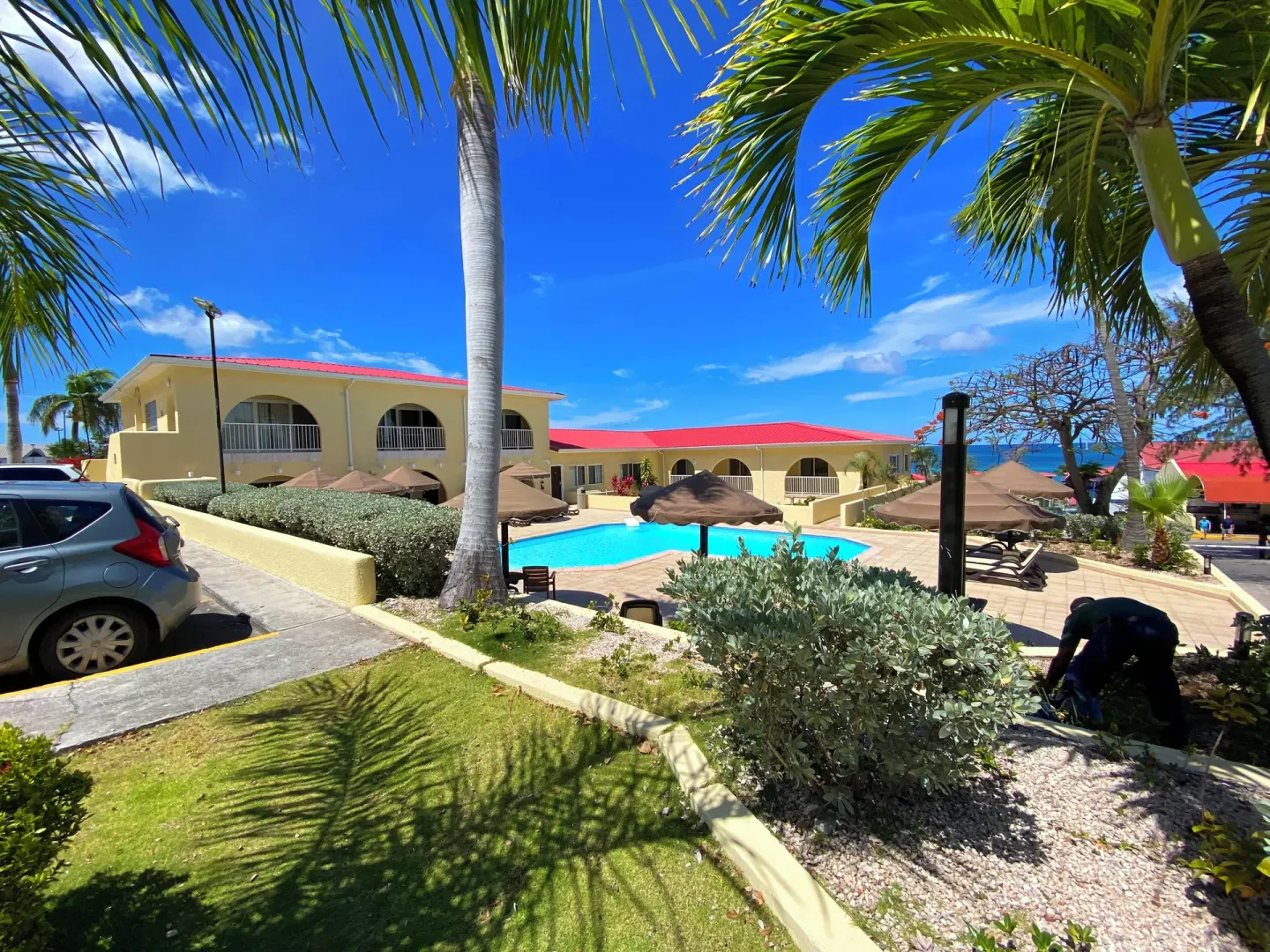 Palm-framed pool area with gardens and red-roofed buildings at Simpson Bay Resort, Marina & Spa.
