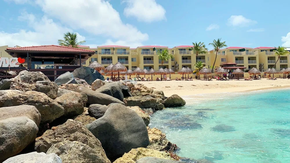 Rocky shoreline, beach umbrellas, and resort buildings at Simpson Bay Resort, Marina & Spa.