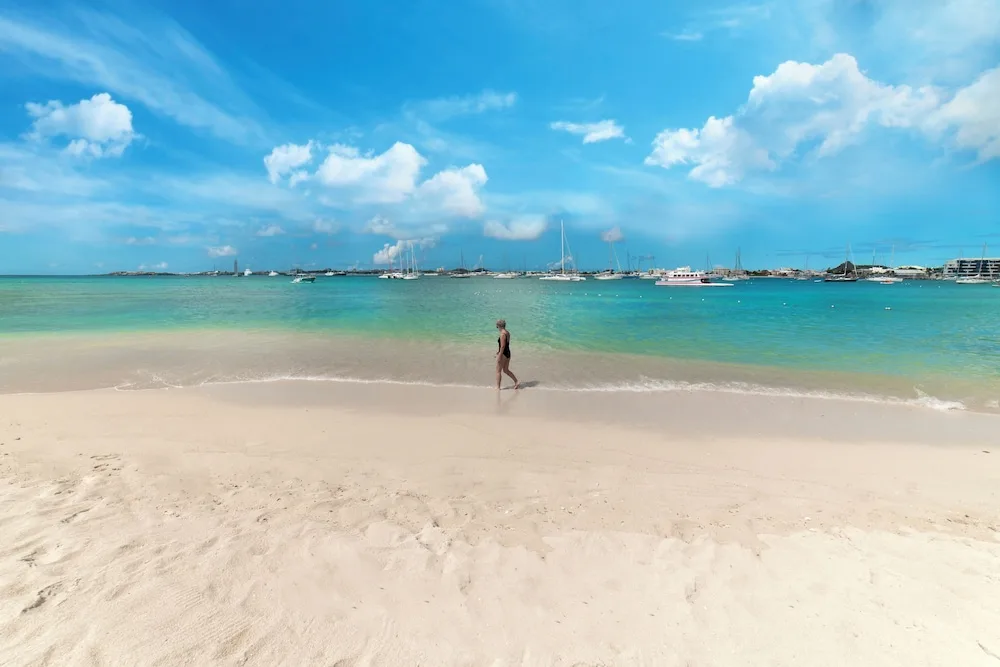 Sandy beach with marina boats across the bay at Simpson Bay Resort, Marina & Spa.