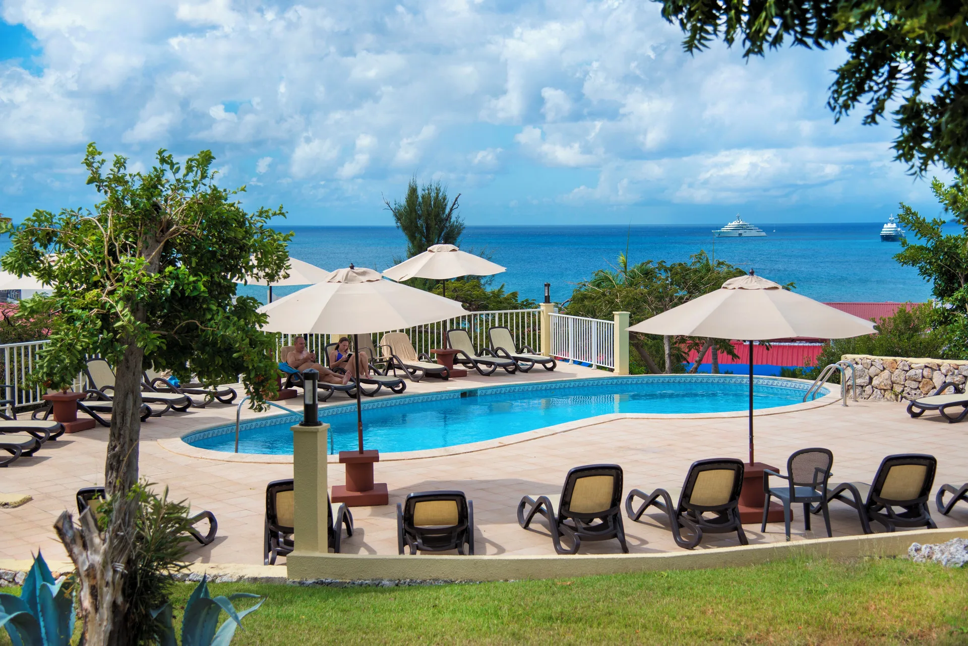 Small pool with umbrellas, lounge chairs, and ocean views at Simpson Bay Resort, Marina & Spa.