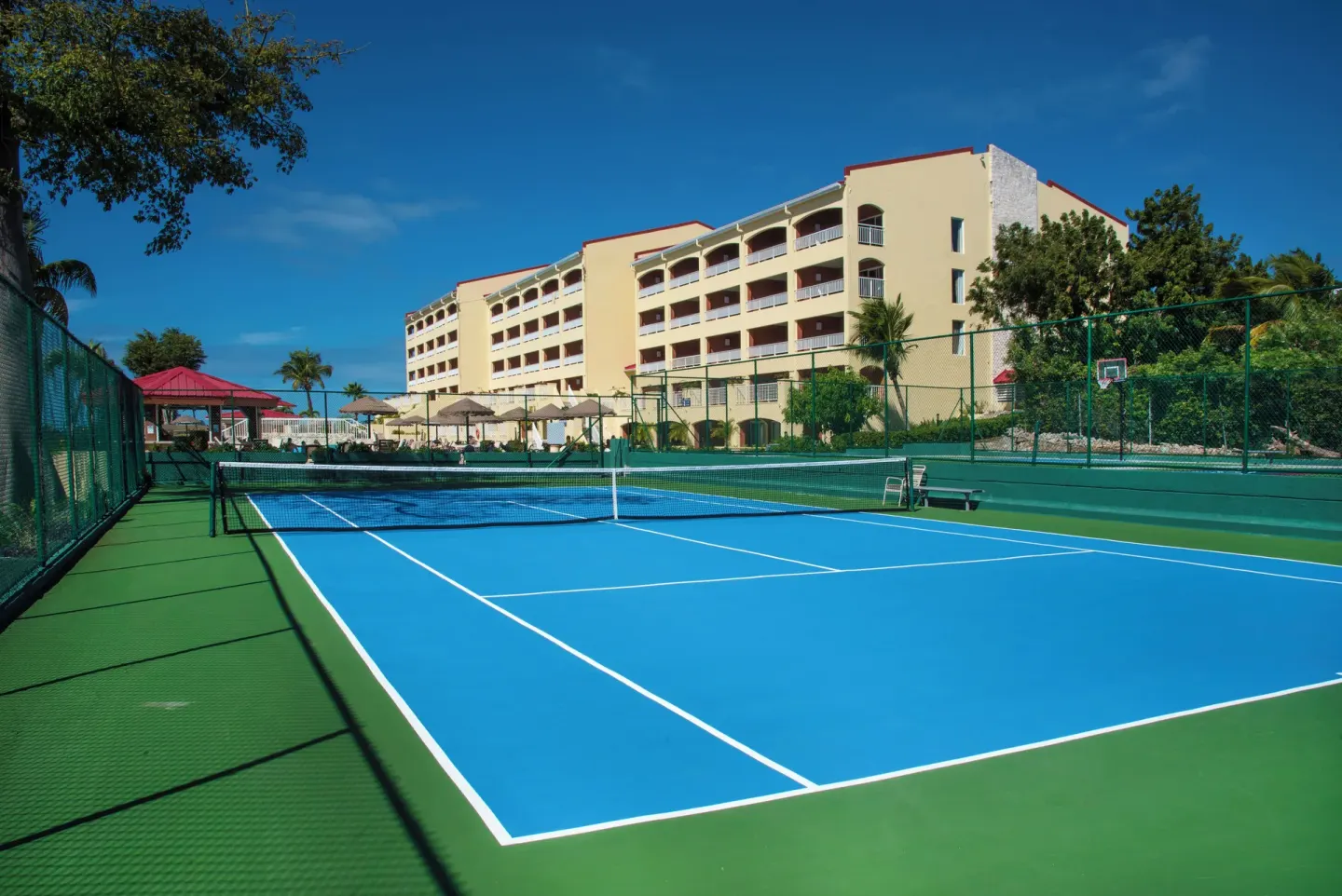 Tennis court with resort buildings behind it at Simpson Bay Resort, Marina & Spa.