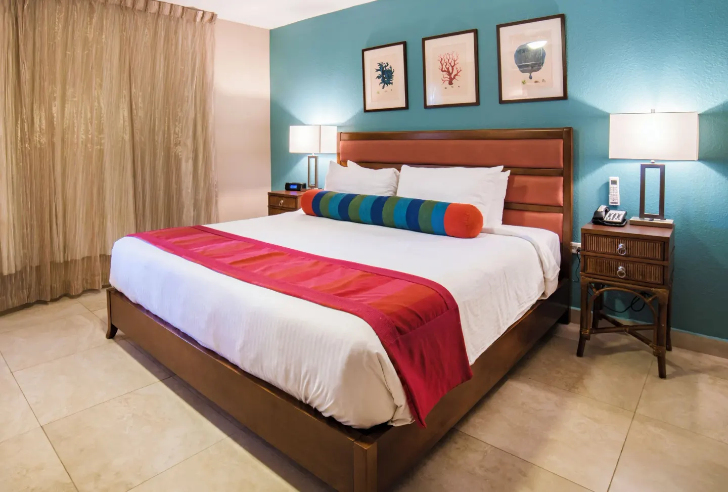 King bed with coral artwork in a deluxe studio at Simpson Bay Resort, Marina & Spa.