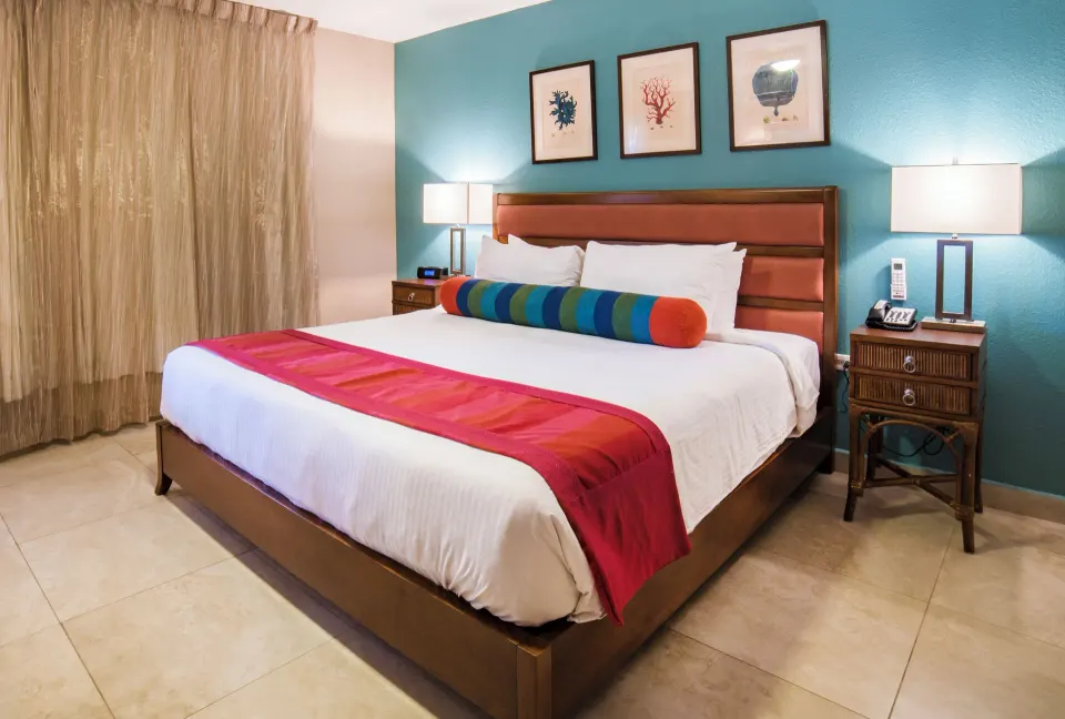 King bed with coral artwork in a deluxe studio at Simpson Bay Resort, Marina & Spa.