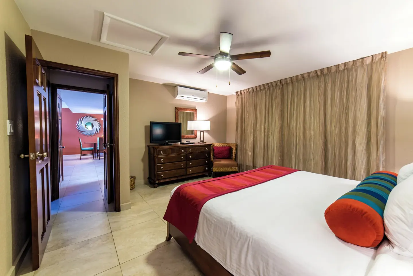 Deluxe Suite bedroom at Simpson Bay Resort, Marina & Spa with king bed, dresser, TV, and patio view.