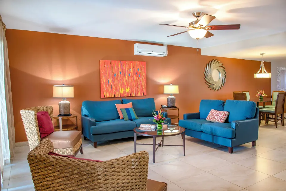 Deluxe Suite living area at Simpson Bay Resort, Marina & Spa with blue sofas, woven chairs, and dining area.