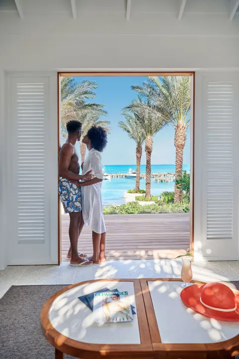 A couple stands in a beachside doorway with palm trees and turquoise water at SLS Baha Mar.