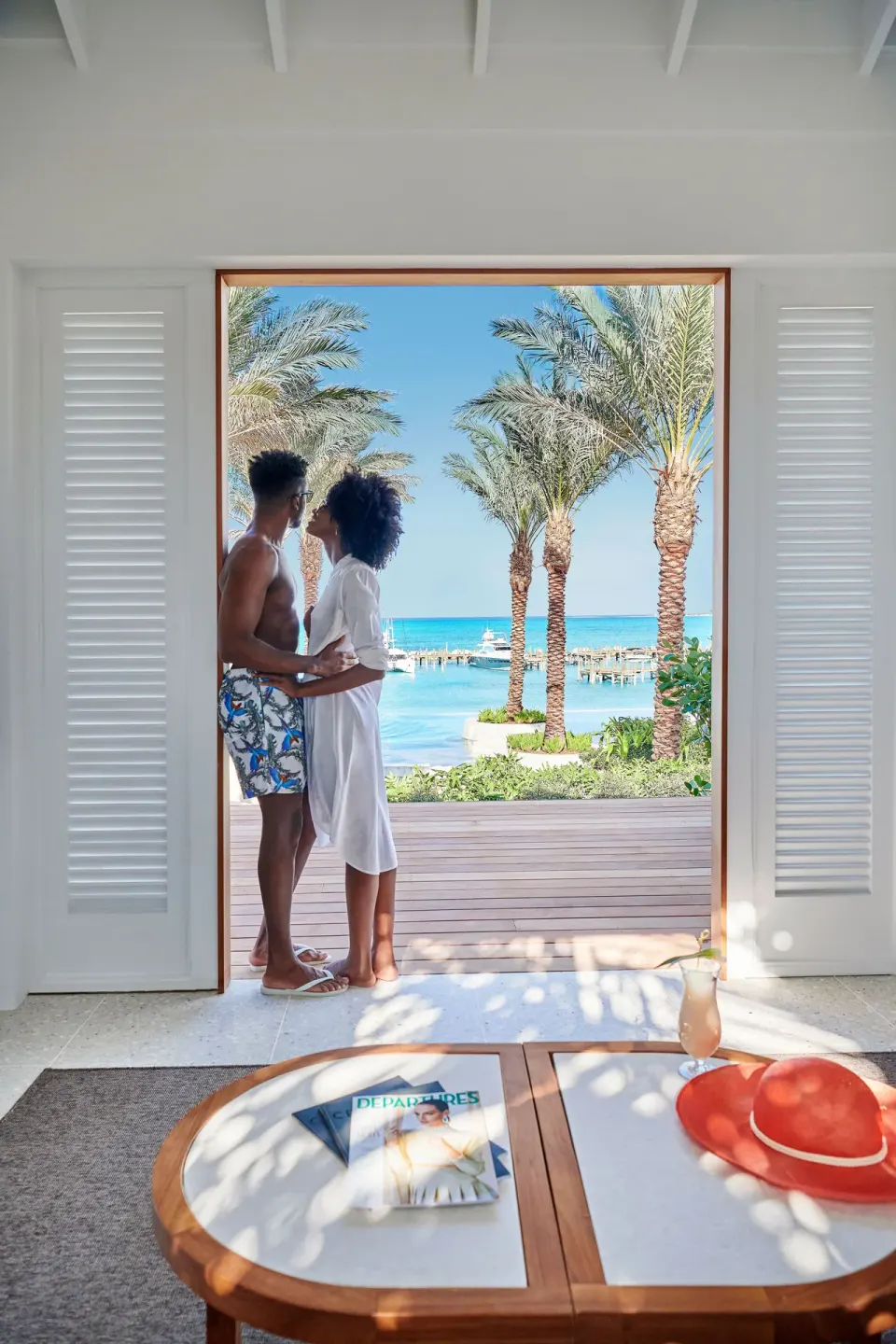 A couple stands in a beachside doorway with palm trees and turquoise water at SLS Baha Mar.
