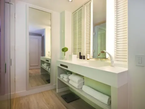 Guest bathroom vanity with mirrors, towels, and shutter details at SLS Baha Mar.