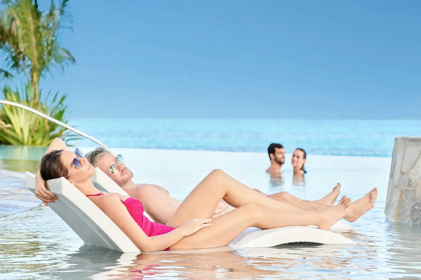 Guests recline on in-water loungers in an infinity-edge pool at SLS Baha Mar.