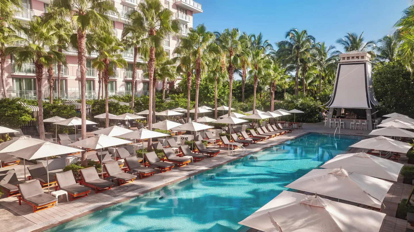 Resort pool with palm trees, loungers, umbrellas, and a pavilion at SLS Baha Mar.
