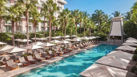Resort pool with palm trees, loungers, umbrellas, and a pavilion at SLS Baha Mar.