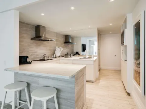 Suite kitchen with marble counters, stools, and stainless hood at SLS Baha Mar.