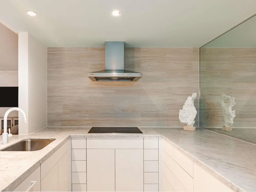 Compact suite kitchen with cooktop, sink, and mirrored wall at SLS Baha Mar.