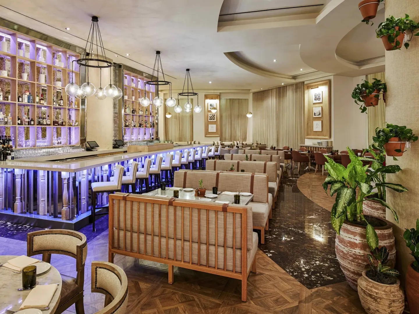 A restaurant bar with glowing shelves and banquette seating at SLS Baha Mar.