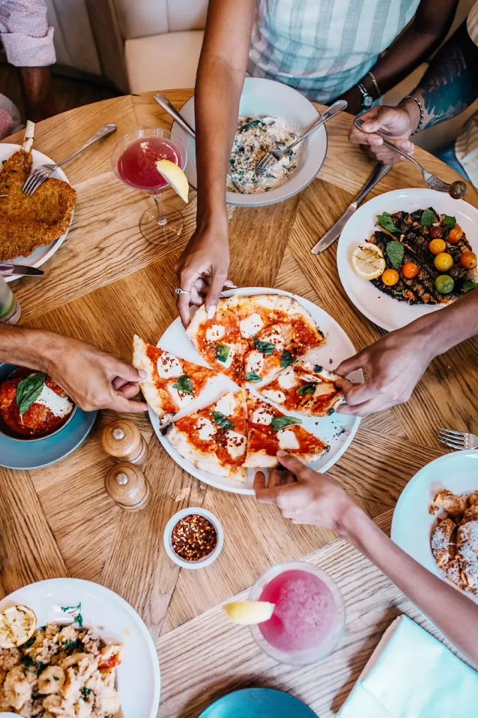 Shared pizza and plates of food on a round dining table at SLS Baha Mar.