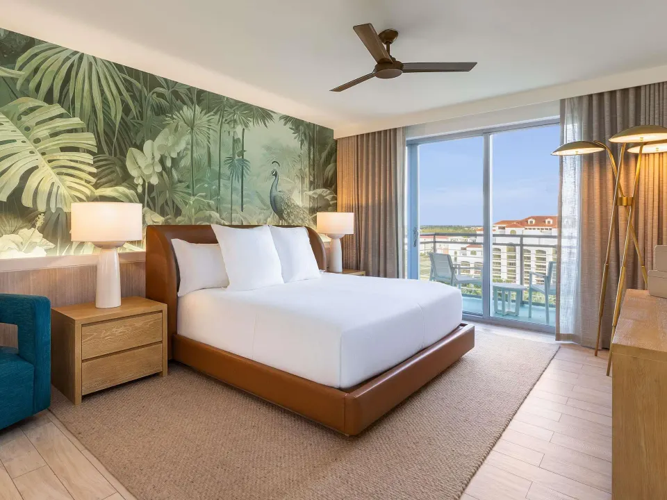 King bed in an Ocean View Two Bedroom Suite at SLS Baha Mar with balcony doors and tropical mural.