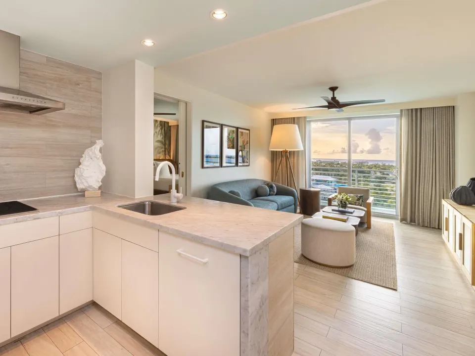 Kitchenette and living room in an Ocean View Two Bedroom Suite at SLS Baha Mar with balcony view.