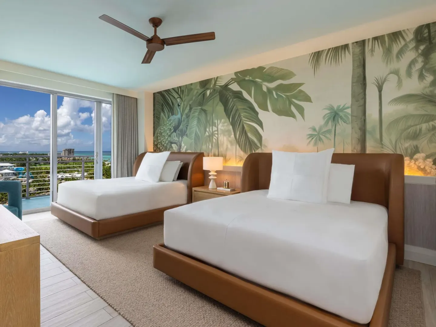 Two queen beds in an Ocean View Two Bedroom Suite at SLS Baha Mar with balcony and sea beyond.