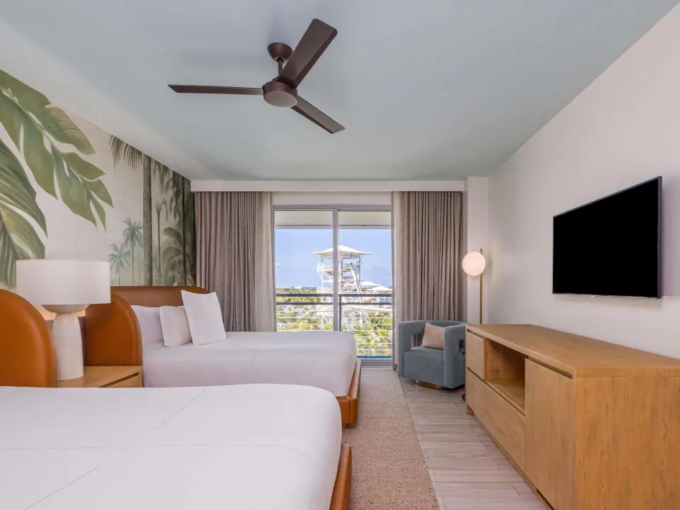 Superior Queens room with two beds, balcony doors, TV, and distant tower view at SLS Baha Mar.