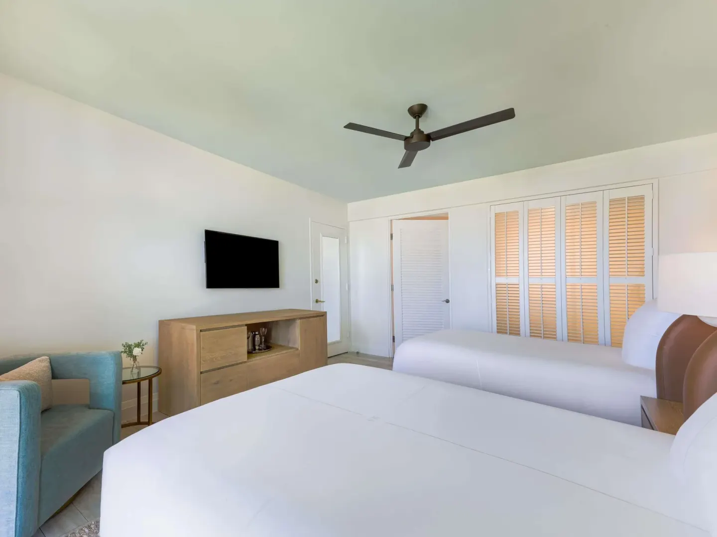 Superior Queens room with two beds, lounge chair, TV, and louvered doors at SLS Baha Mar.