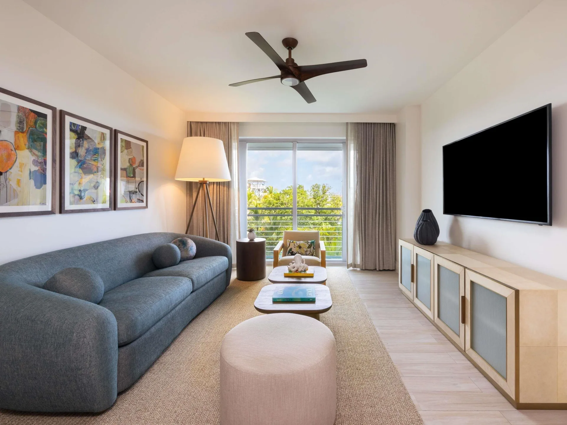 Superior Suite living room with sofa, balcony doors, and TV at SLS Baha Mar.