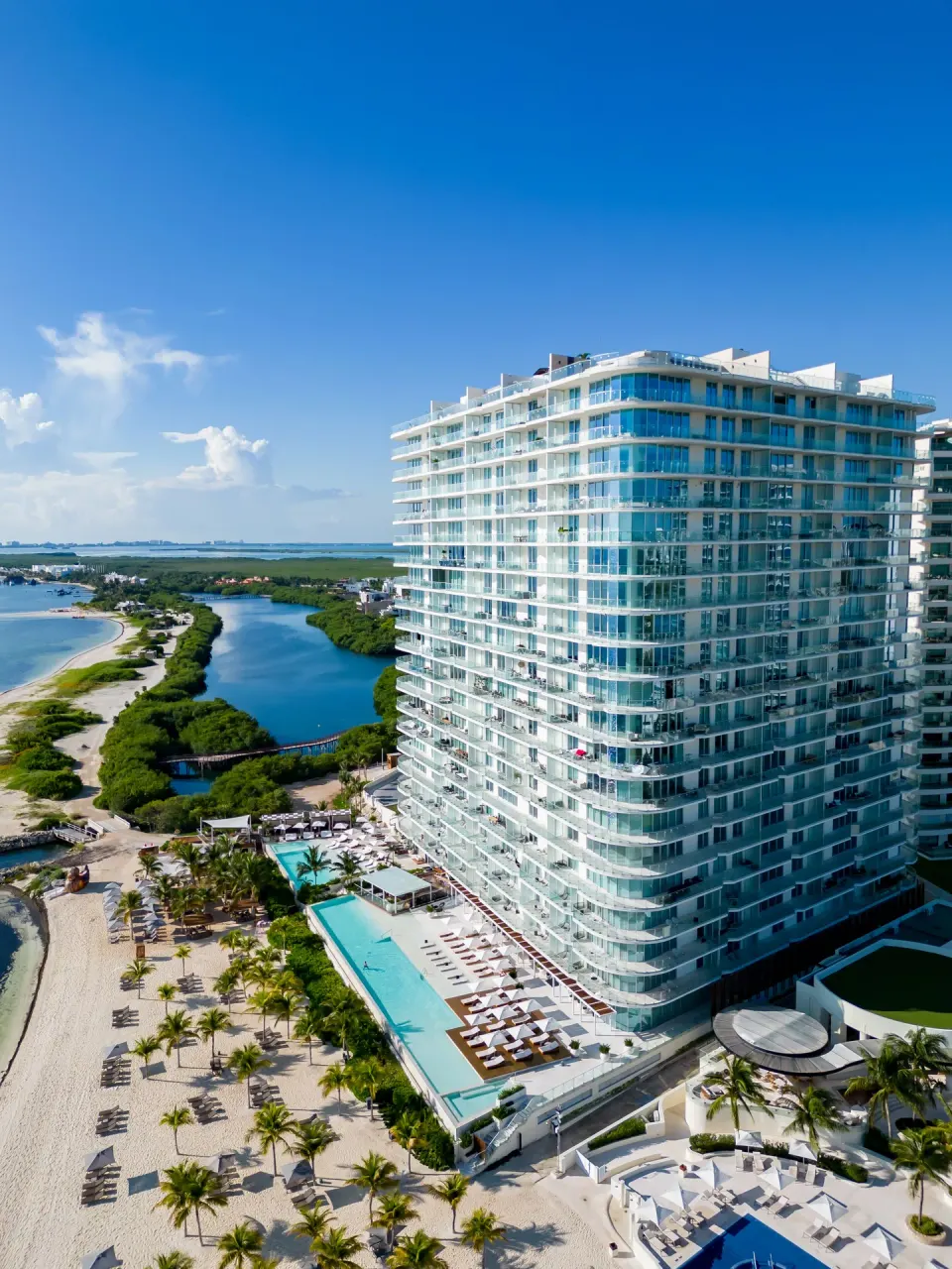 Aerial view of the beachfront tower, pools, beach, and lagoon at SLS Cancun.
