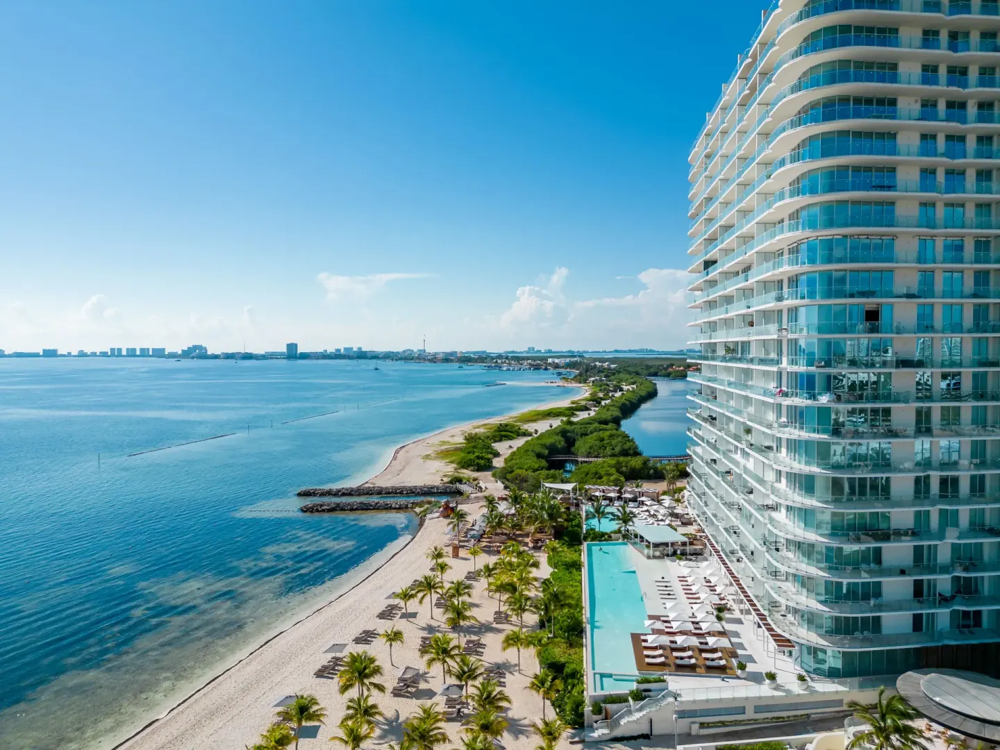 The beachfront tower, pool deck, and shoreline are seen from above at SLS Cancun.