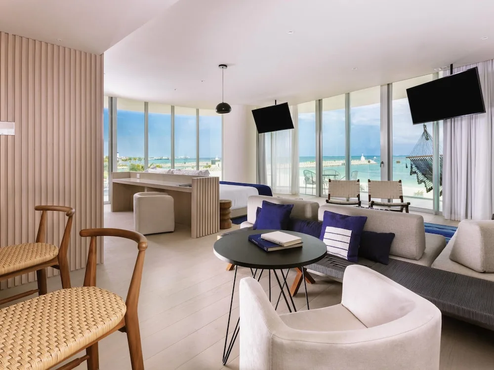 Corner suite with lounge seating, bed, balcony, hammock, and water views at SLS Cancun.
