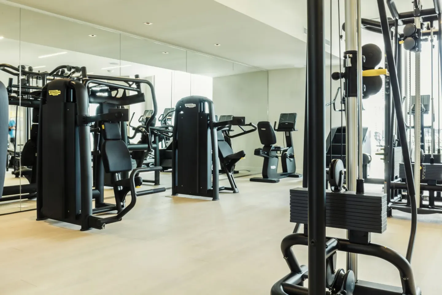 Fitness room with strength machines, cardio equipment, and mirrored wall at SLS Cancun.