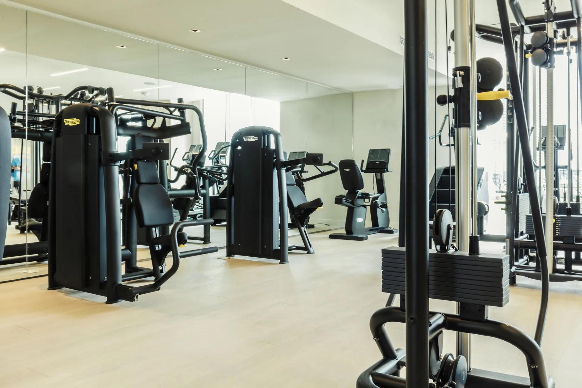 Fitness room with strength machines, cardio equipment, and mirrored wall at SLS Cancun.