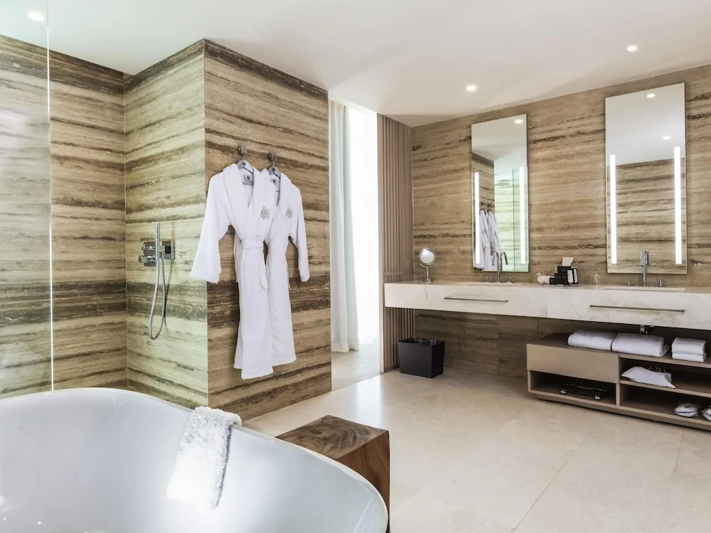 Guest bathroom with freestanding tub, shower, robes, and double vanity at SLS Cancun.
