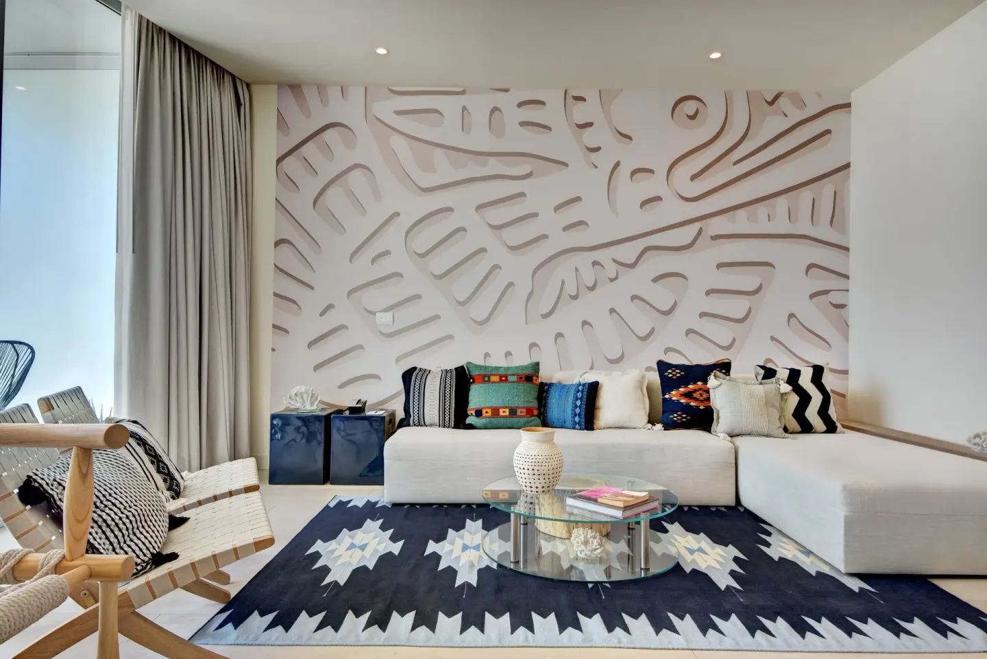 Guest room lounge with sectional sofa, patterned rug, and glass coffee table at SLS Cancun.