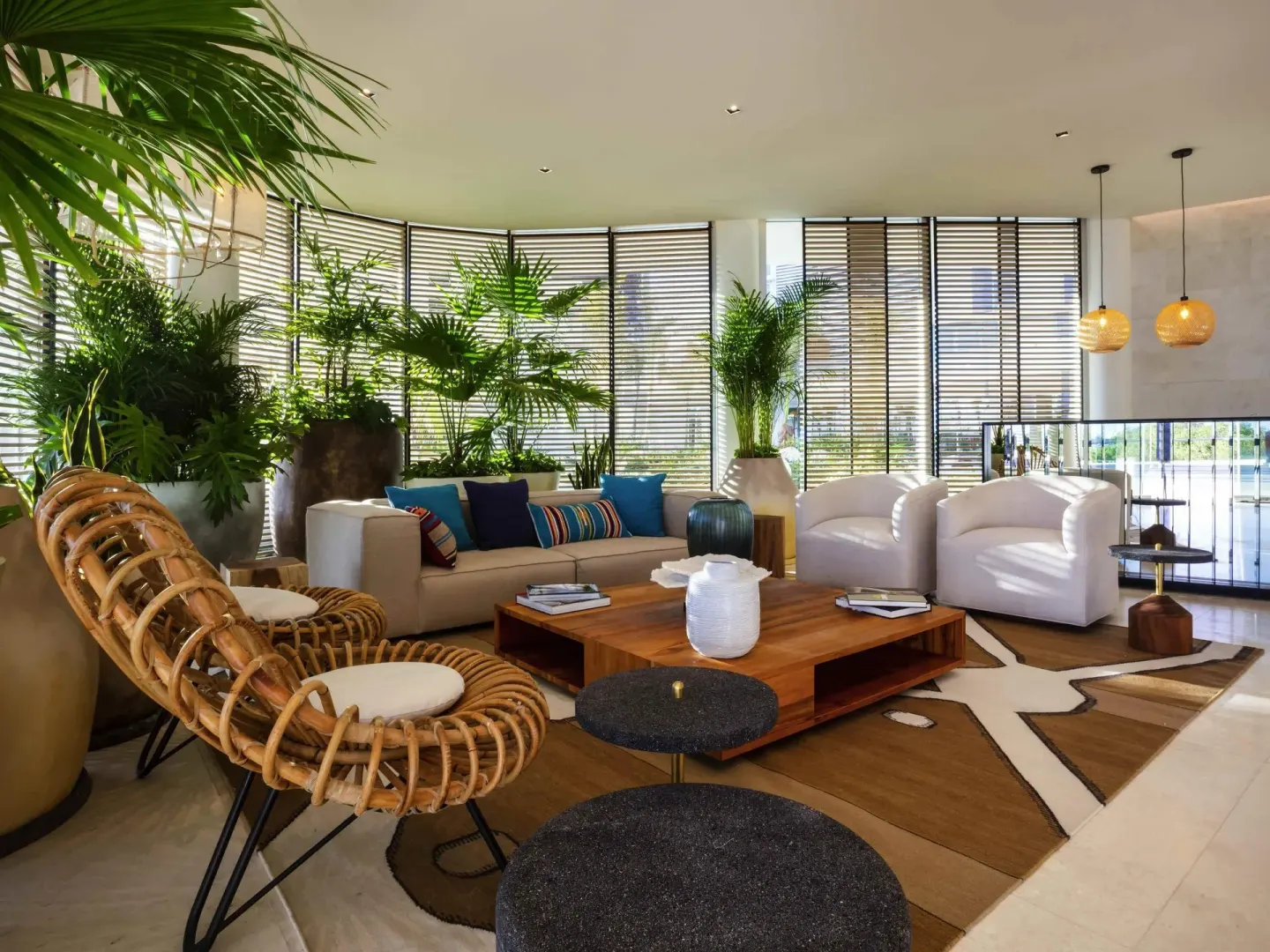 Lounge seating with plants, woven chair, and wood tables inside SLS Cancun.