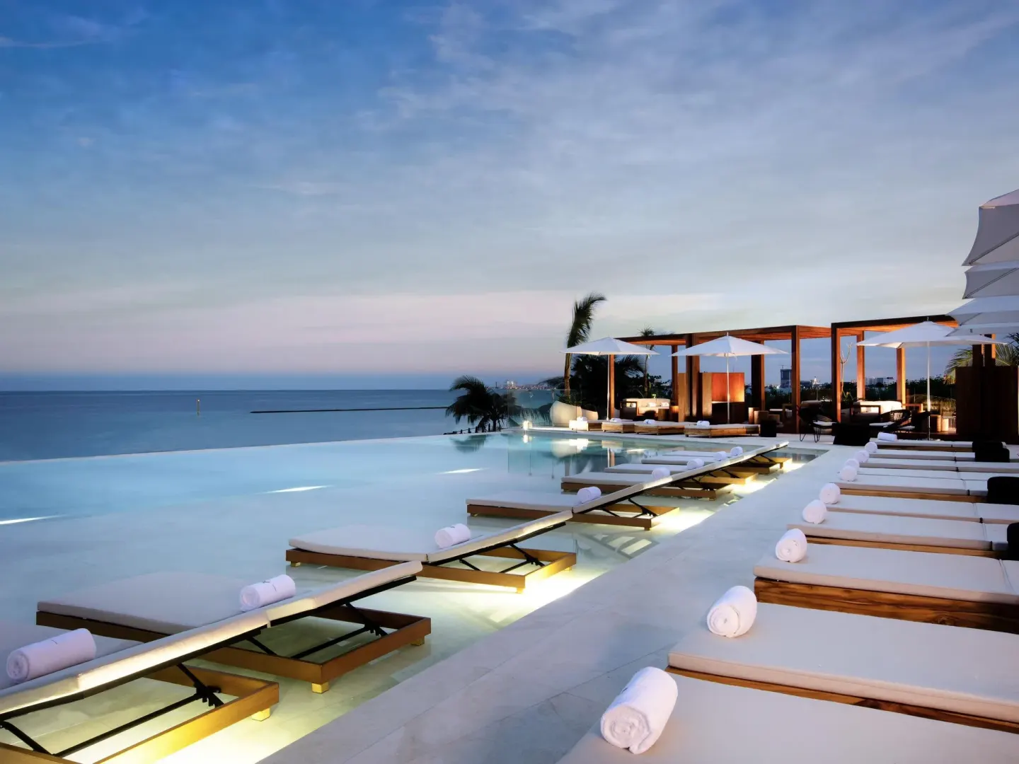 Infinity pool with submerged loungers and ocean views at SLS Cancun.