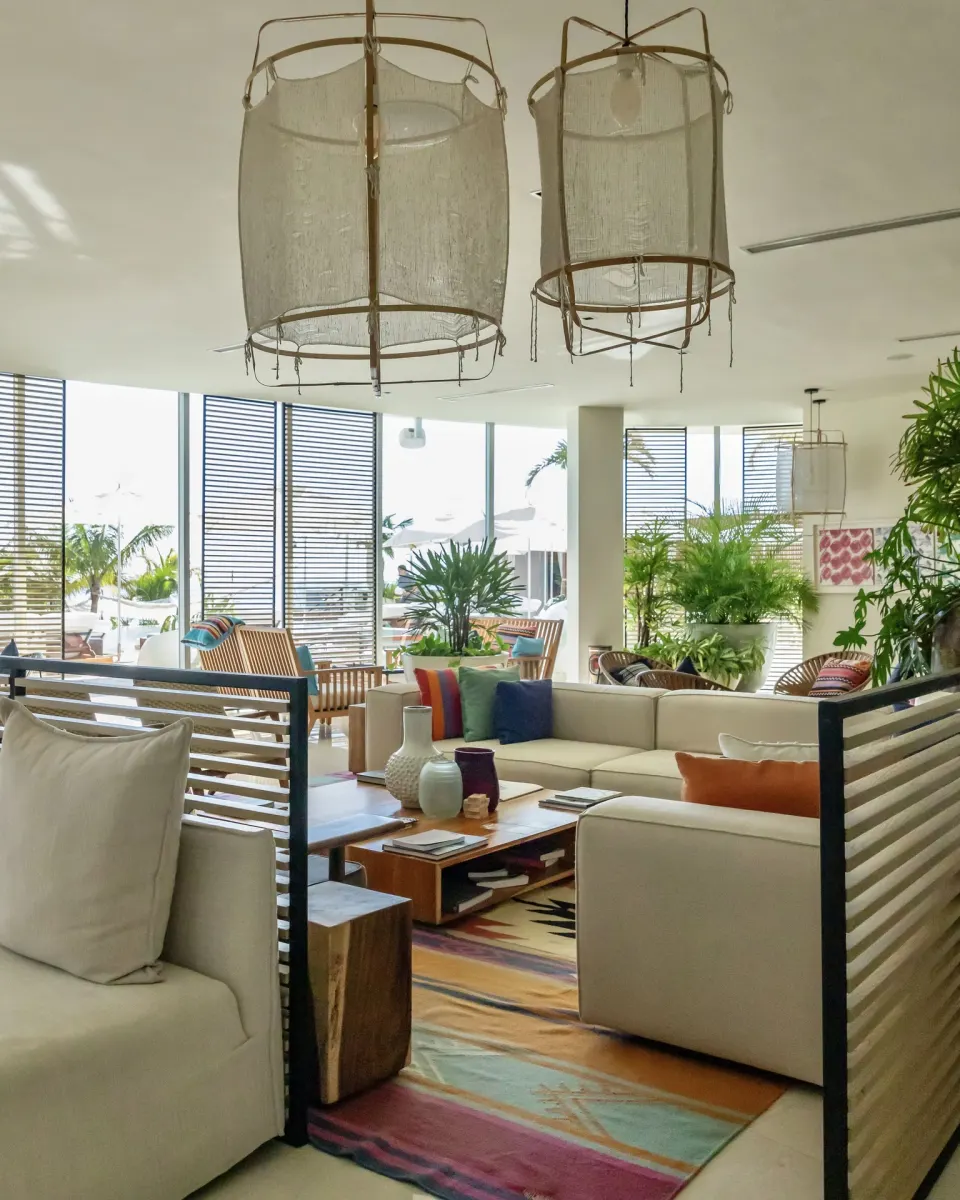 Bright lobby lounge with sofas, plants, and woven pendant lights at SLS Cancun.