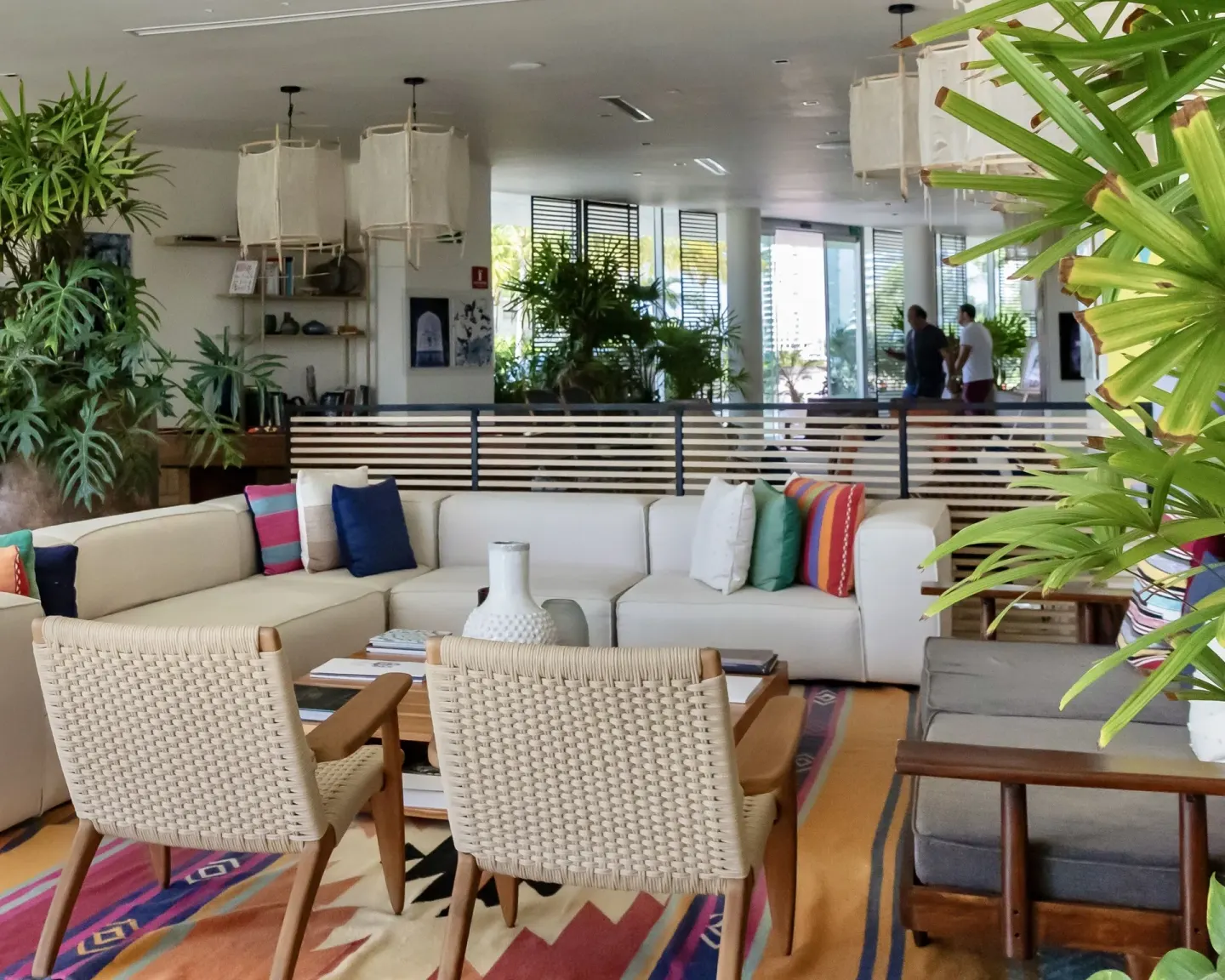Lobby lounge with woven chairs, cream sectional sofas, and greenery at SLS Cancun.