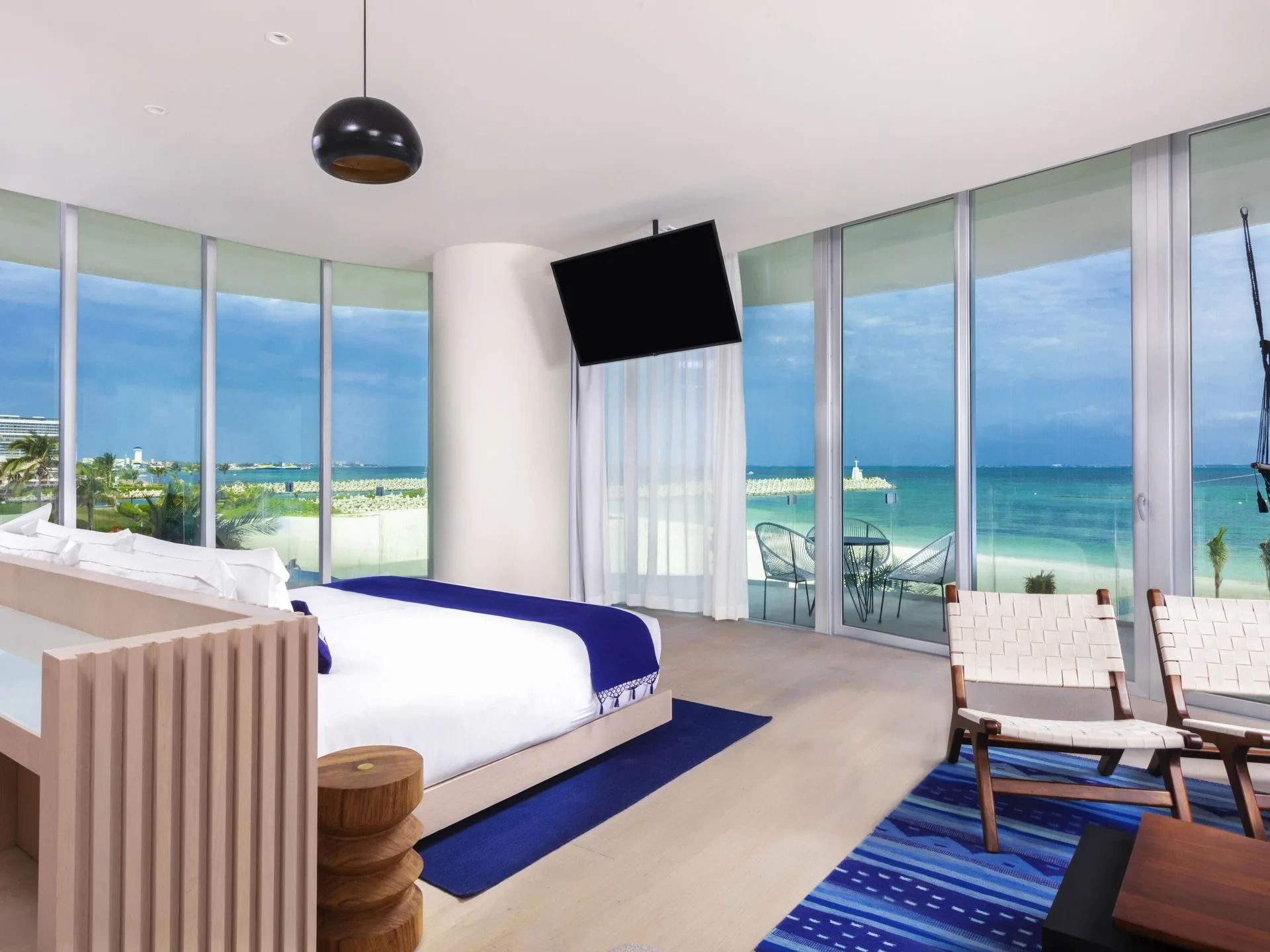 Guest room with king bed, seating, balcony, and ocean-facing windows at SLS Cancun.