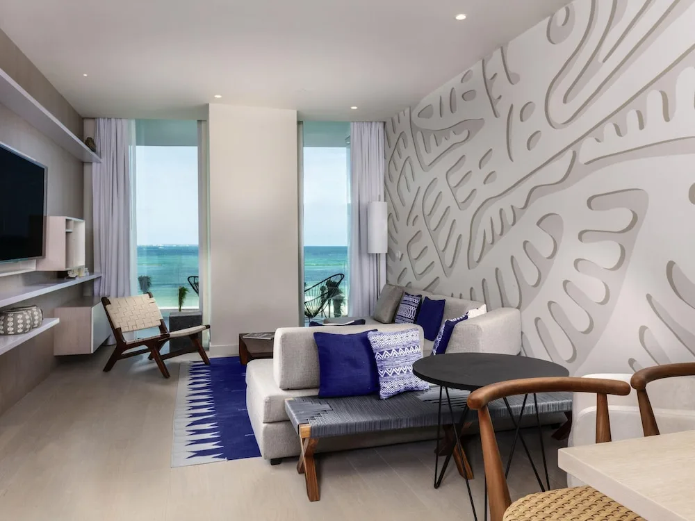 Living area with sofa, TV, balcony, and ocean view at SLS Cancun.