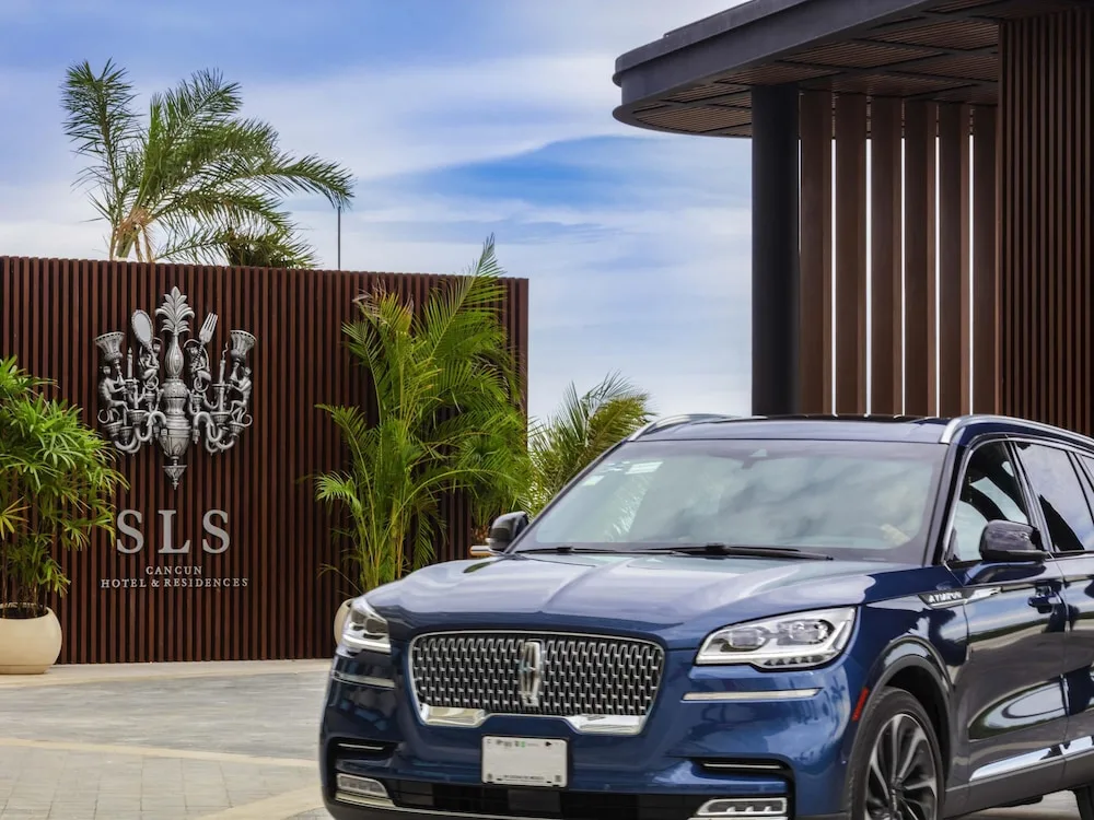 Entrance sign and arriving SUV at the driveway of SLS Cancun.