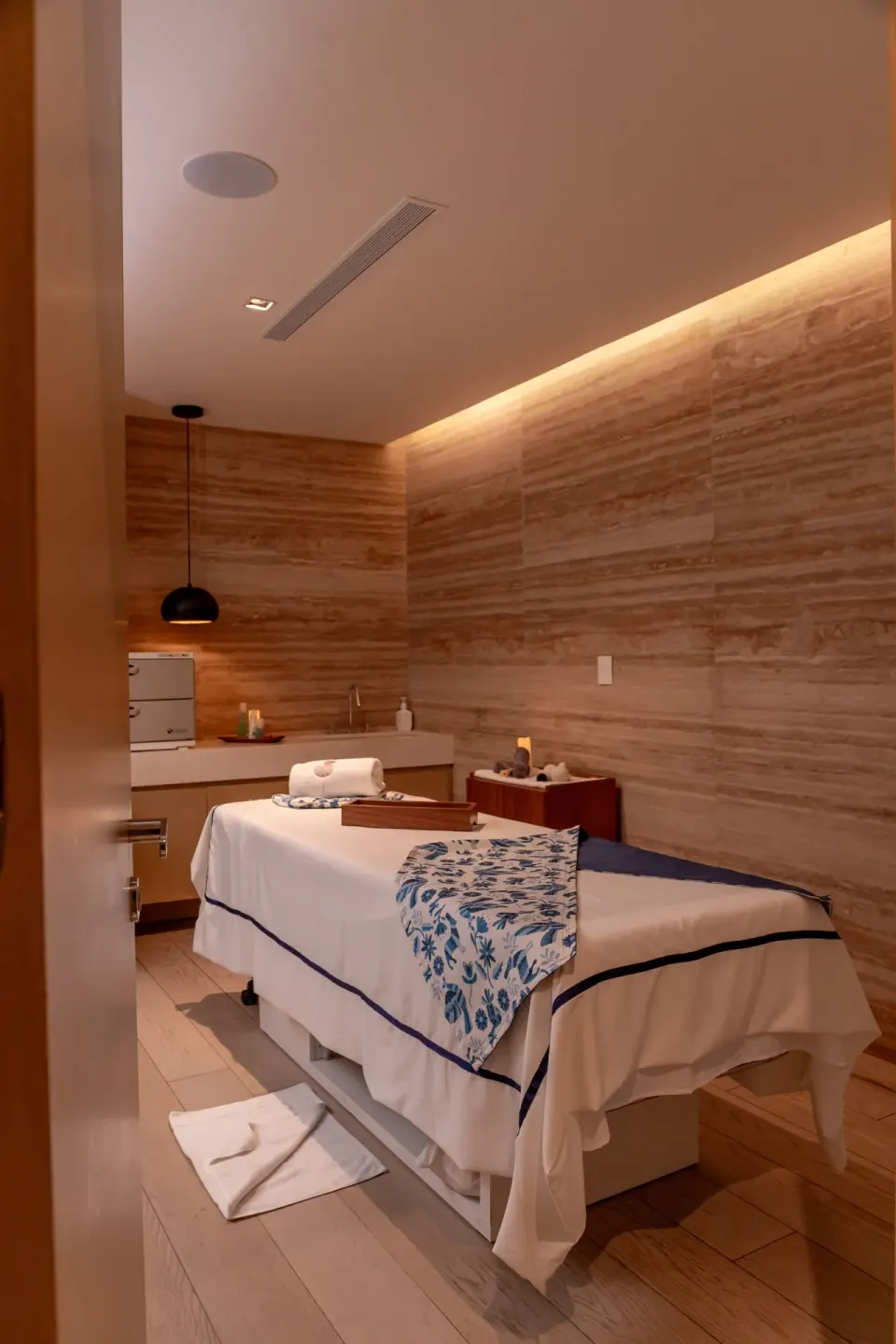Spa treatment room with massage table, towels, and warm wood walls at SLS Cancun.