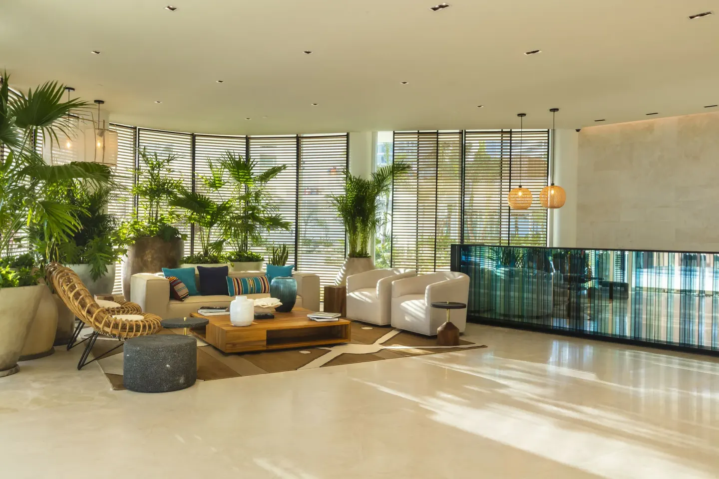 Sunlit lobby seating area with white armchairs and tropical plants at SLS Cancun.