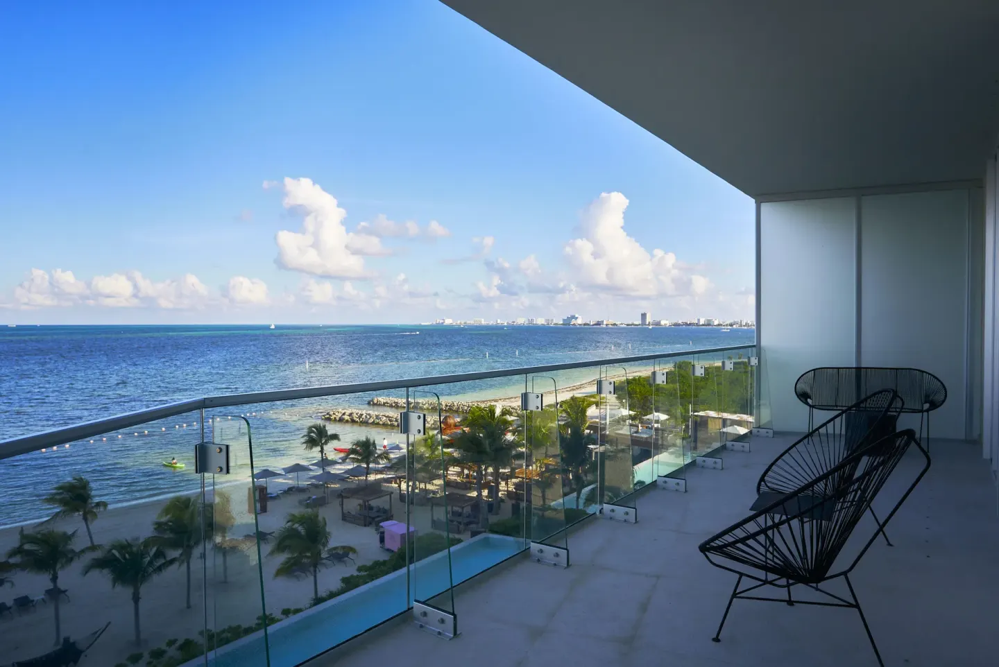 Deluxe Room Oceanfront balcony at SLS Cancun with chairs overlooking the beach and Caribbean Sea.