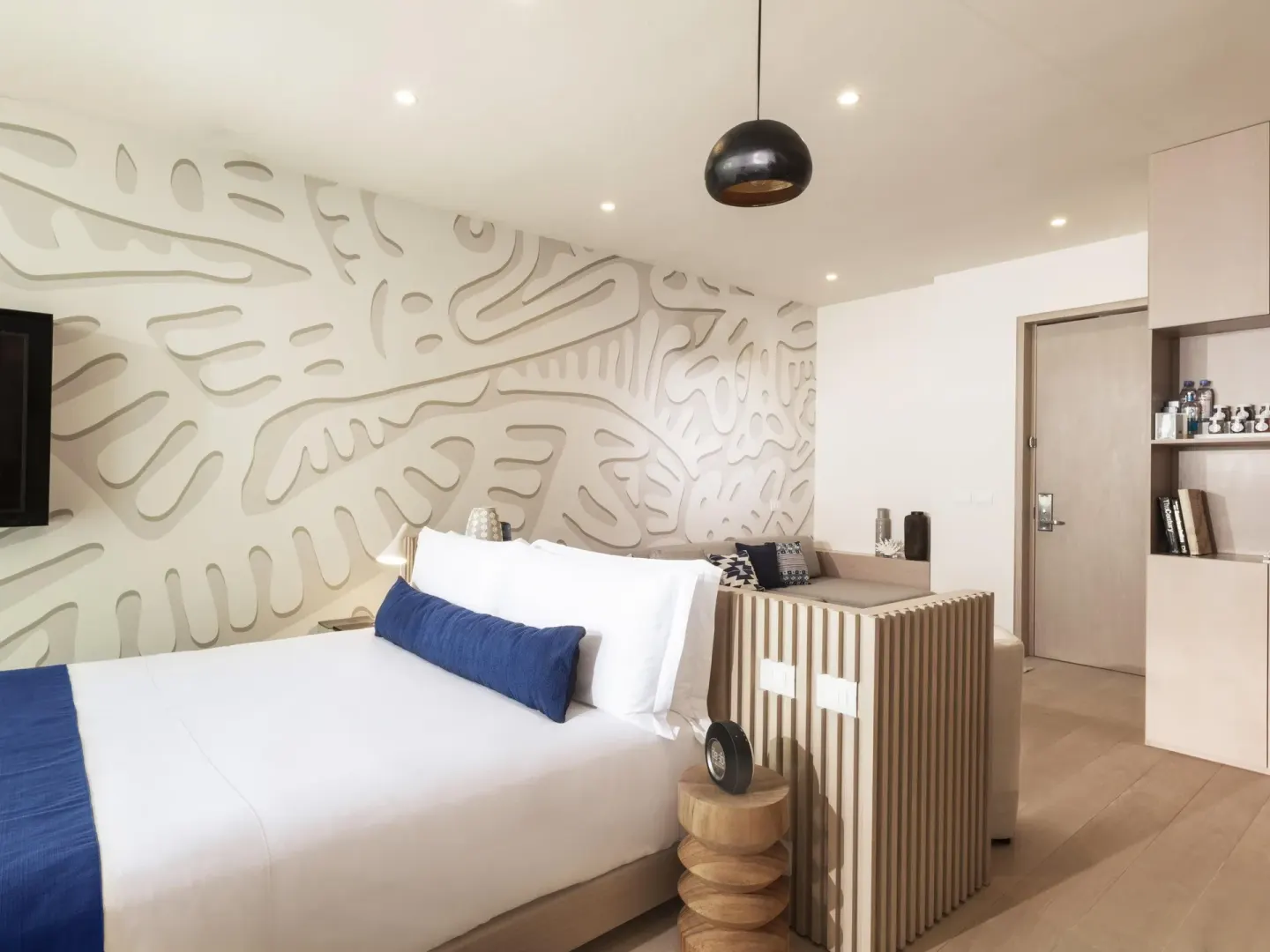 Deluxe Room Oceanfront at SLS Cancun with king bed, carved wall detail and entry area.