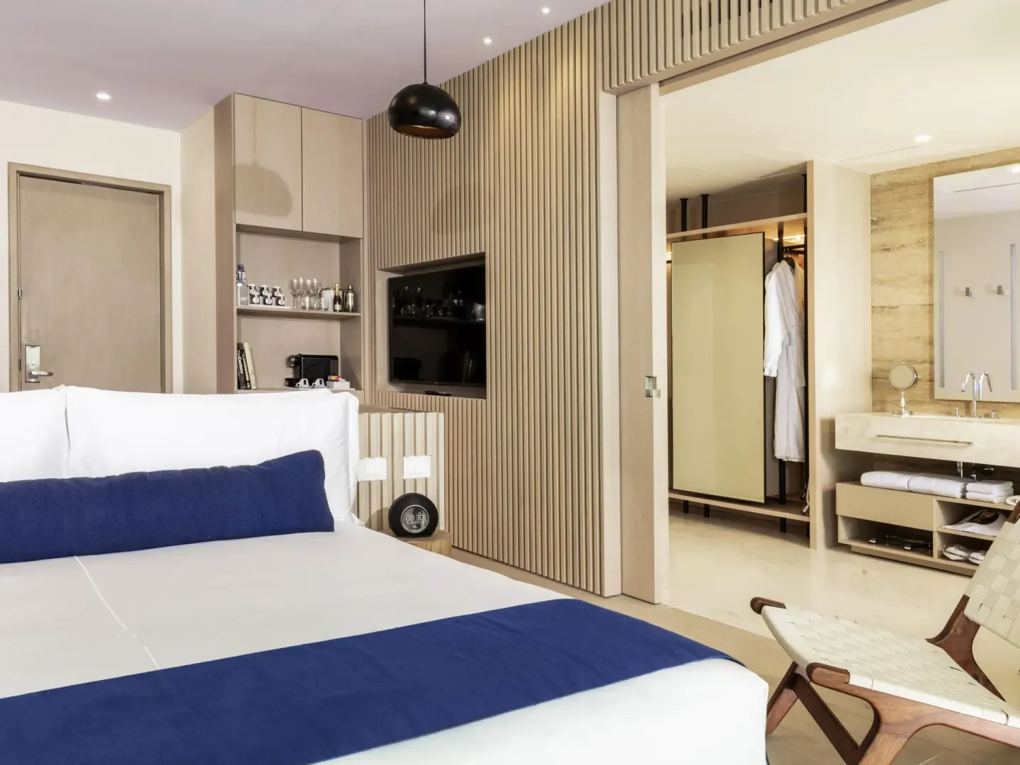 Deluxe Room Oceanfront at SLS Cancun with king bed, TV wall, chair and open vanity area.