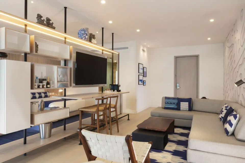 Deluxe oceanfront suite living area with sofa, TV wall and desk at SLS Cancun.