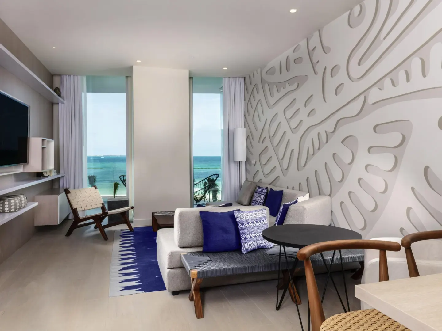 Deluxe oceanfront suite seating area with textured wall and ocean windows at SLS Cancun.