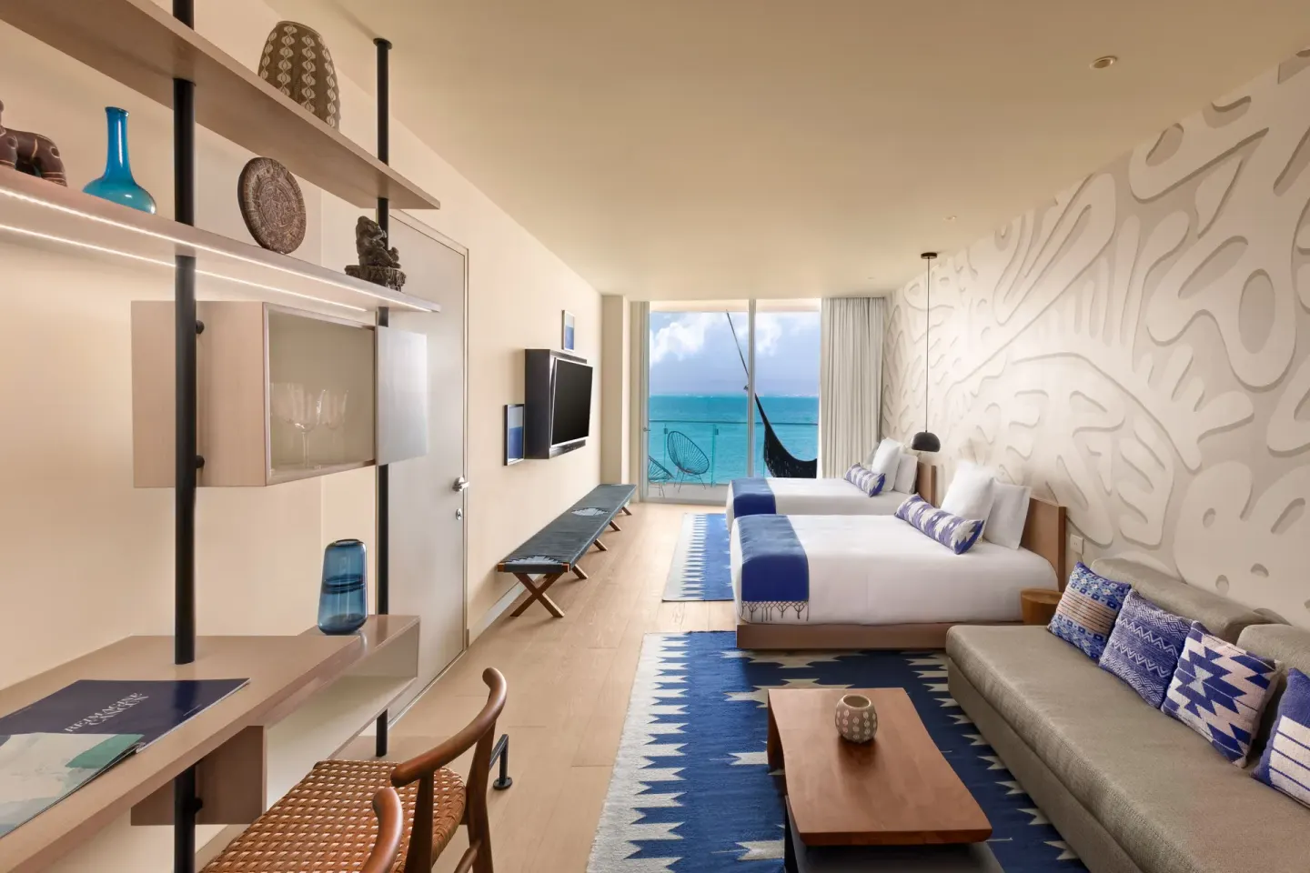 Deluxe oceanfront suite with two beds, sofa and balcony view of the water at SLS Cancun.