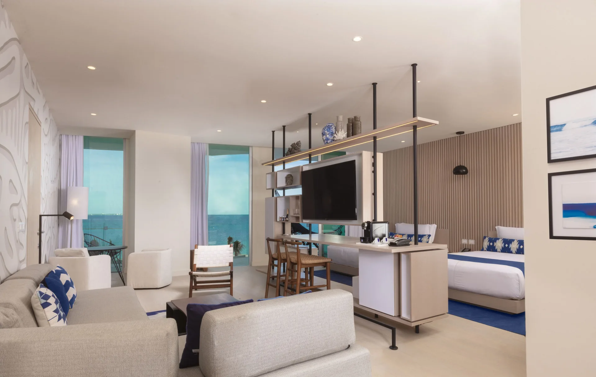 Deluxe oceanfront suite with sofa seating, two beds and ocean-facing windows at SLS Cancun.